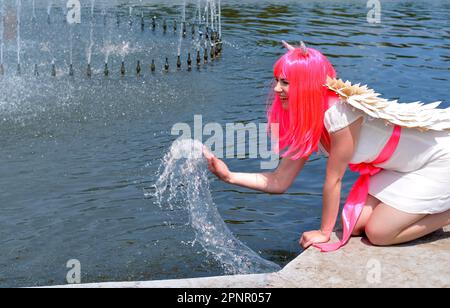 attractive woman  in demon costume cooling near the fountain in hot weather Stock Photo