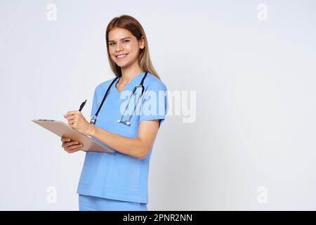 Portrait of smiling woman doctor taking notes making medical with clipboard isolate over white background. Stock Photo