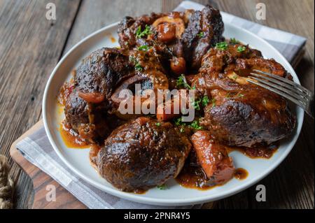 Braised beef shanks or leg slices with carrots and gravy on a plate Stock Photo