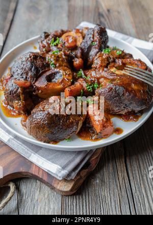 Braised beef shanks with gravy on a plate isolated on wooden table Stock Photo