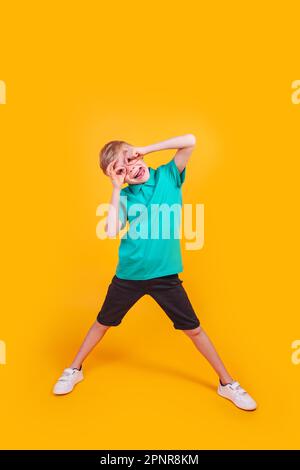 Little kid boy showing ok-sign like glasses fooling on yellow background Stock Photo