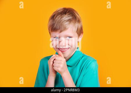 Closeup portrait of sneaky sly scheming kid boy on yellow background Stock Photo