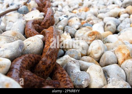 Chain, thick and rusty on the shingle beach in Yport Stock Photo