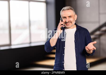 Happy elder grandfather talking on mobile phone, resting on comfortable sofa, speaking, smiling, laughing, chatting, contact family. Senior grey haire Stock Photo
