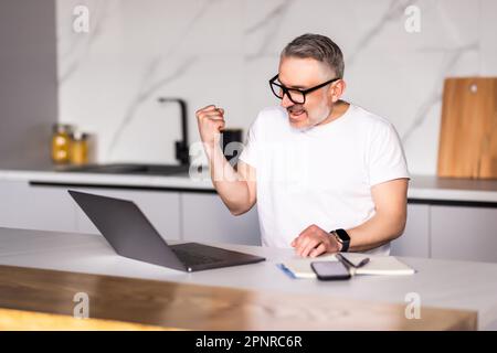 Middle age handsome businessman wearing tie sitting using laptop at the office celebrating surprised and amazed for success with arms raised and open Stock Photo