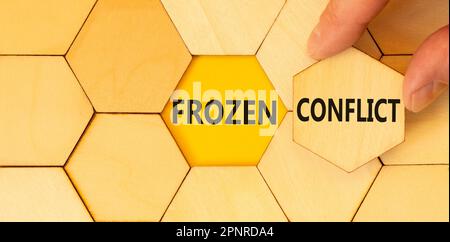 Frozen conflict symbol. Concept words Frozen conflict typed on wooden puzzles. Beautiful yellow table yellow background. Businessman hand. Business an Stock Photo