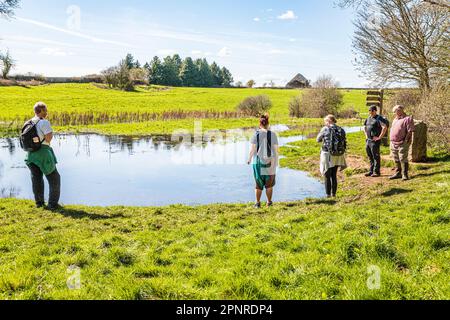 People at the start of the Thames Path at the source of the River Thames at Thames Head on the Cotswolds near Kemble, Gloucestershire UK. Stock Photo