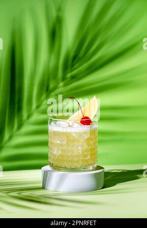 Whiskey sour trendy alcoholic cocktail with bourbon, lemon juice, egg white and ice in glass on bright green background, hard light, shadow pattern fr Stock Photo