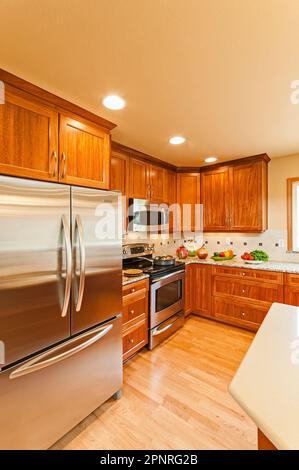 Wood cabinets, countertops, appliances, and hardwood floors in this contemporary house remodel. Stock Photo