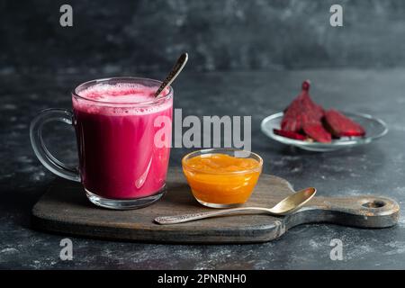 Beetroot vanilla latte from fresh beetroot juice blended with vanilla and milk in a transparent cup on the table in cafe, close up. Trendy healthy dri Stock Photo