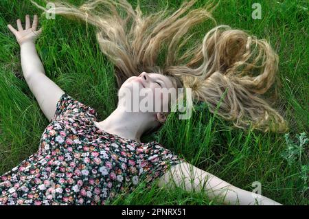 teenage girl with long hair relaxing on the grass at summer day Stock Photo