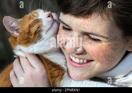 close-up portrait of happy freckled girl and red cat outdoors Stock Photo
