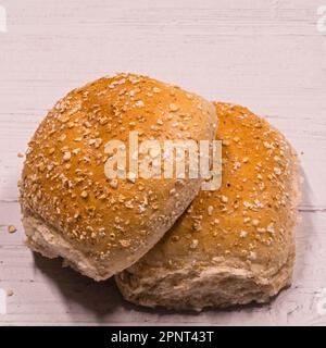 Two brown wheaten Oatmeal rolls on top[ of a wooden board Stock Photo
