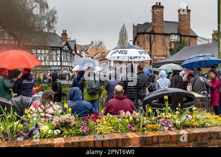 People under umbrellas wait in the village for the finish of the 2023 annual Lymm Duck Race. Stock Photo