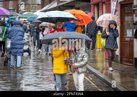 Oriental family walk along a village street under umbrellas in the rain Stock Photo