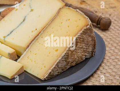 Cheese collection, French cheeses Morbier semi-soft cow milk cheese with black mold layer and Tomme de Savoie with grey rind close up Stock Photo