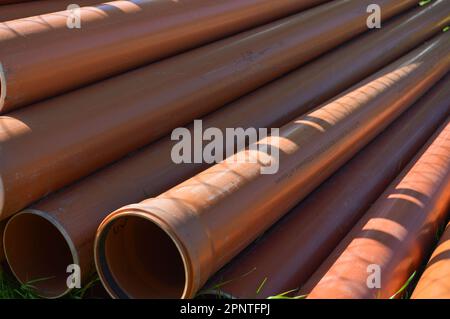 Orange plastic industrial polypropylene thick plumbing pipes with large diameter gaskets with flanges. Stock Photo