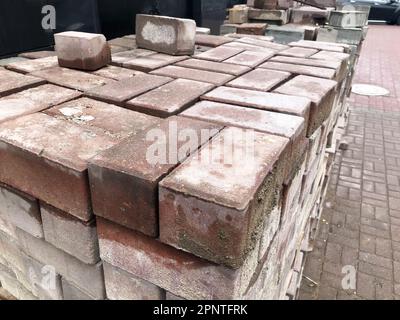 Paving stone red cement tile for laying road construction, pavement on wooden pallets at a construction site. Stock Photo
