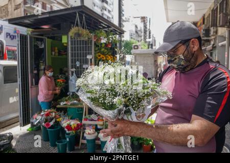 Jhonatan Almao, right, who is learning the skills to be a florist from Marcia Veliz, left, holds a bouquet in Caballito, Buenos Aires, Argentina on October 25, 2021. Almao, who immigrated from Venezuela in 2020, says all flowers have different meanings and are used for special occasions, to ingratiate, or to ask for forgiveness. (Lucila Pellettieri/Global Press Journal) Stock Photo