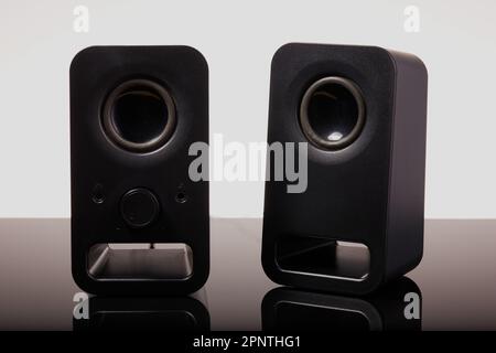 Set of cool black micro speakers on a black surface with a white background. Stock Photo