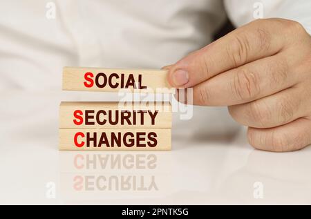 Business concept. In the hands of a person and on a reflective surface are wooden blocks with the inscription - Social security changes Stock Photo