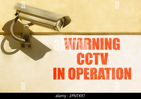 Video surveillance and security. A CCTV camera is installed on the wall of the building, next to it is written - Warning CCTV in operation Stock Photo