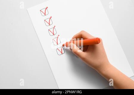 Woman marking on checklist box with orange marker Stock Photo