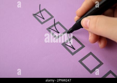 Woman marking on checklist box with black marker Stock Photo