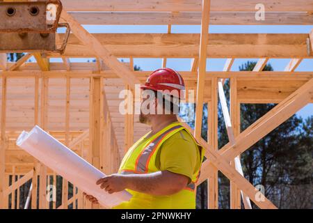 On building site construction engineer checks the quality of wooden frame using architecture blueprint plan Stock Photo