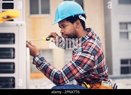 Black man, technician and maintenance with engineering and ac repair with handyman working with tools on roof. Fix air conditioner, male electrician Stock Photo