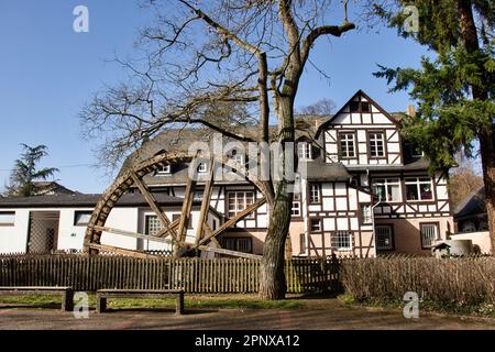 Bad Kreuznach, Germany - February 25, 2021:  Wooden water wheel in front of a white and brown building on a sunny winter day in Bad Kreuznach, Germany Stock Photo