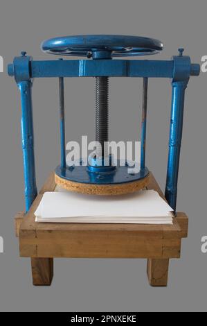 Screw bookbinding press over wooden stand. Isolated over grey background Stock Photo