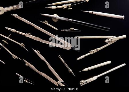 Compass for drawing. Set of old different compasses. Retro metal compasses and drafting tools on a black background. Drawing pen. Tool for study draw Stock Photo