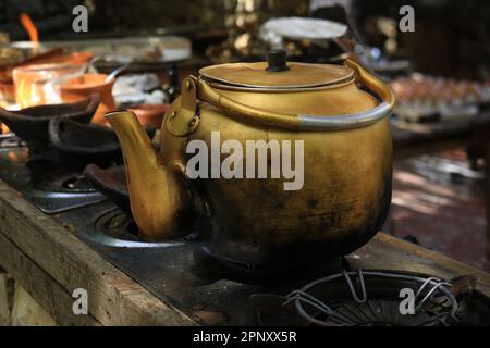 A brass coffee kettle brewing on a stove. Stock Photo
