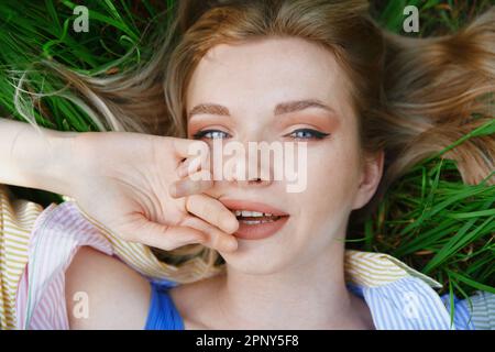 Carefree young blond woman lying in grass and enjoying summer time Stock Photo