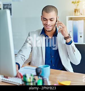 I will email you our latest business reports. a young businessman talking on a cellphone in an office. Stock Photo