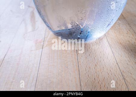 A close up view of condensation on the side of a glass jug of water on a table. Stock Photo
