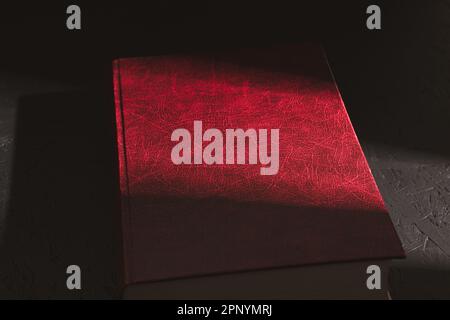 An old red book, A hard ray of the sun falls on an old red book. Sunbeam on the book. Close-up Stock Photo