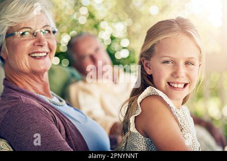 I love coming to grannys. Cropped portrait of a young girl sitting outside with her grandparents. Stock Photo