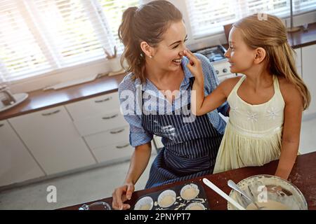 Let me powder your nose. a mother and her daughter baking in the kitchen. Stock Photo