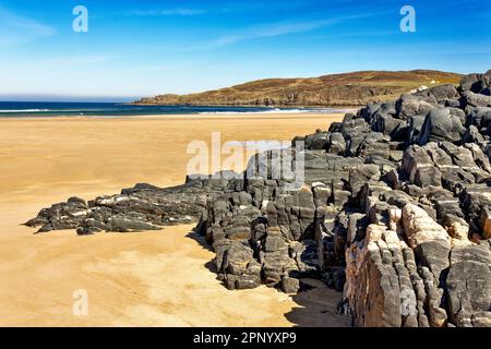 Torrisdale Bay Sutherland Scotland a blue sky and volcanic rock formation on the endless sandy beach and a blue green sea Stock Photo