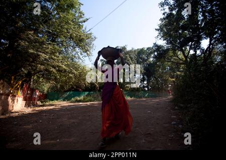 A lady construction worker, labour walking with cement on her head. Stock Photo