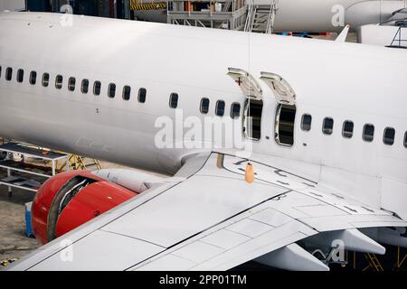 Commercial airplane under heavy maintenance. Side view of plane fuselage with emergency exits and wing. Stock Photo