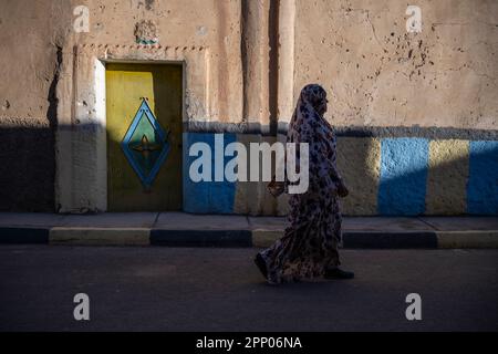 Silhouette of a woman walking in front of the door of a house decorated with colorful traditional Berber motifs. Stock Photo