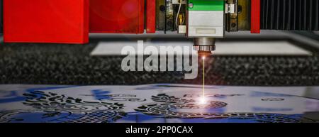 Industrial laser cut machine while cutting the sheet metal with the sparking light. Stock Photo