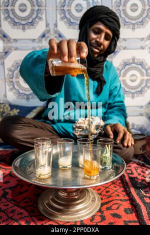 Berber man dressed in djellaba and black turban serving tea in the traditional way. Stock Photo