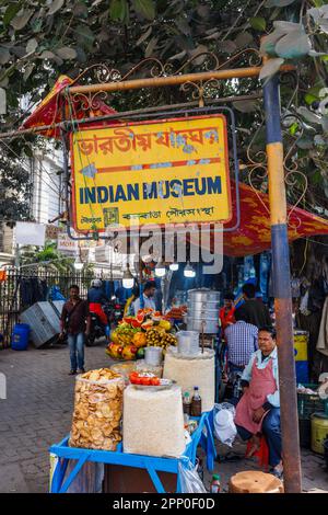 Name sign and street food stall seller by the entrance of the Indian Museum in the New Market Area of Taltala, Kolkata (Calcutta), West Bengal, India Stock Photo