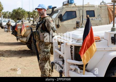 MALI, Gao, Minusma UN peace keeping mission, Camp Castor, german army Bundeswehr, german blue helmet soldier in desert camouflage uniform equipped with Heckler and Koch machine gun HK G36 on patrol, German flag at military vehicle Stock Photo