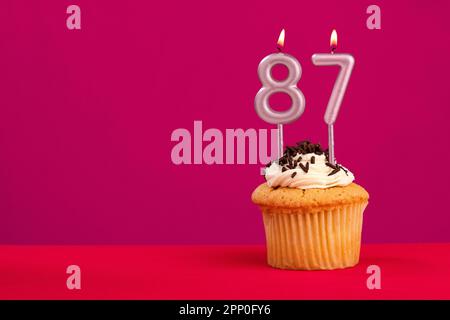 Birthday cake with candle number 87 - Rhodamine Red foamy background Stock Photo