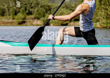 close-up man canoeist on canoe single rowing training on lake Stock Photo